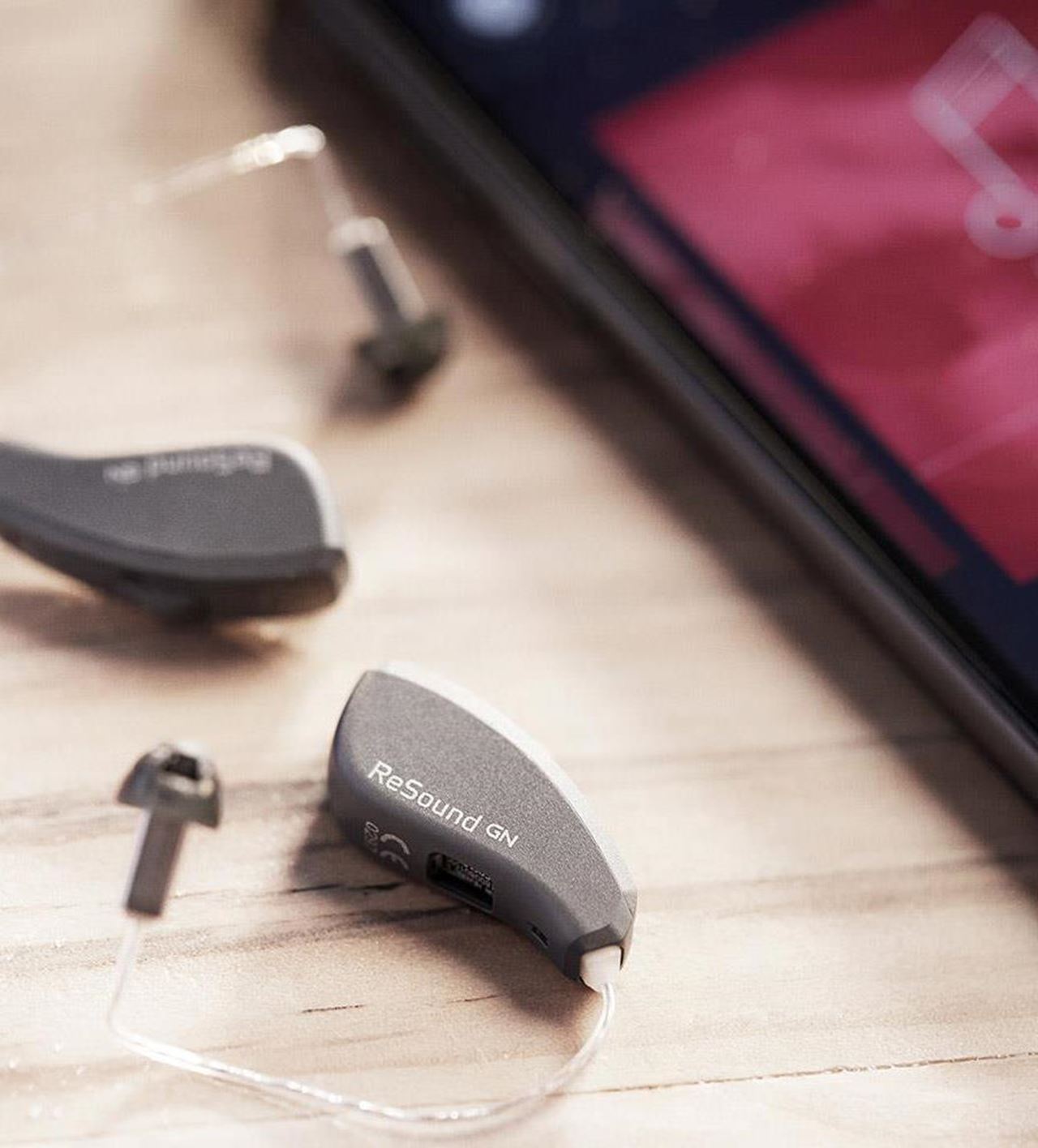 A small rechargeable hearing aid resting in its charging case, fitted at our Whitchurch, Cardiff clinic
