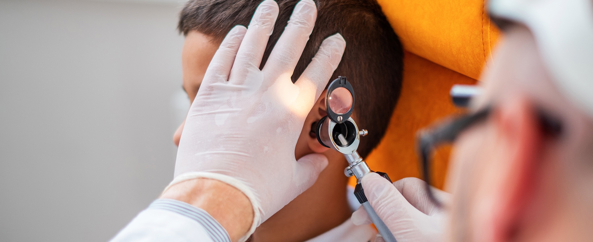 An audiologist gently examining a young child's ear with a handheld otoscope